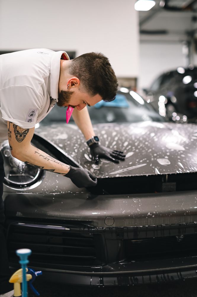 Professional installer applying protective film to a sports car hood